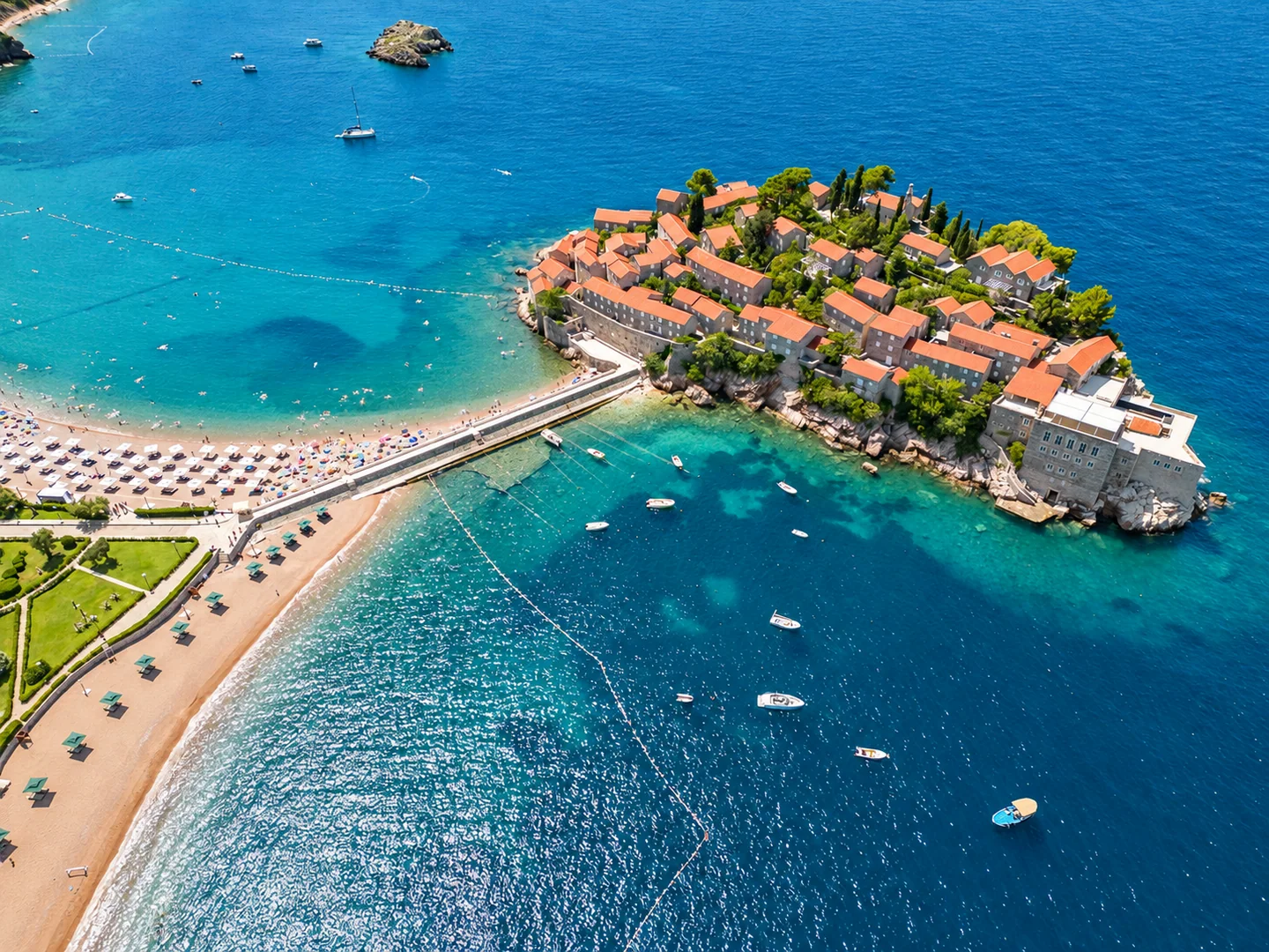 Sveti Stefan with stone villas, red roofs and clear Adriatic water