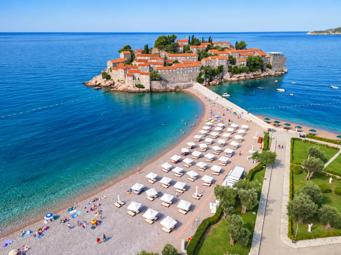 Plaža Sveti Stefan sa suncobranima pod vedrim plavim nebom